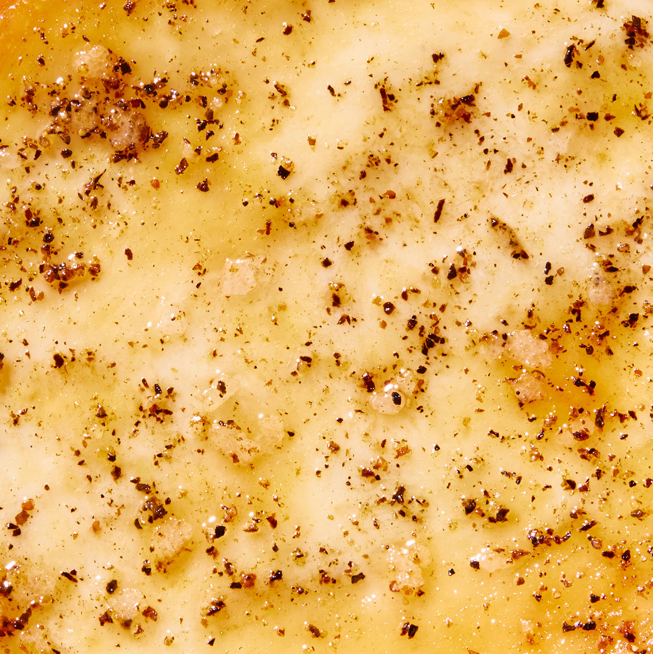 Close-up of a creamy yellow sauce with specks of black pepper
